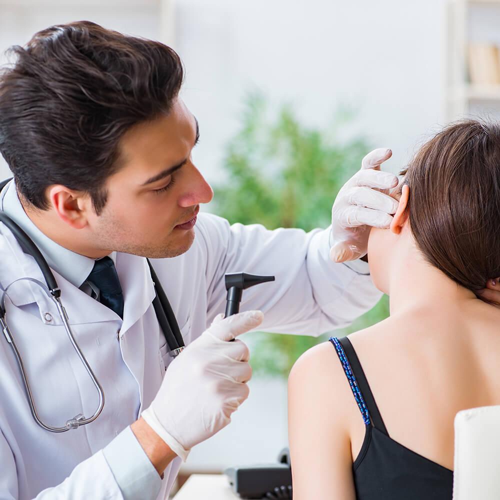 audiologist inspecting patient with otoscope